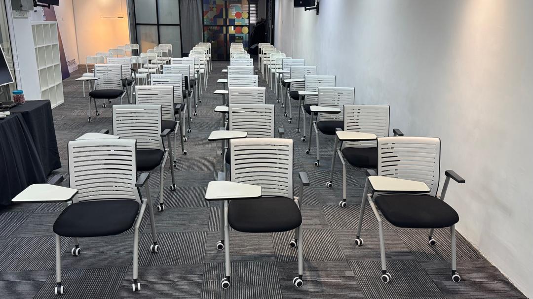 Training hall with seminar-style rows and tablet-arm chairs